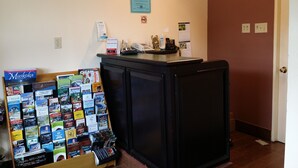 Un espace d’accueil comprenant une horloge, un tableau encadré, un certificat et divers dépliants d’information disposés sur un comptoir.