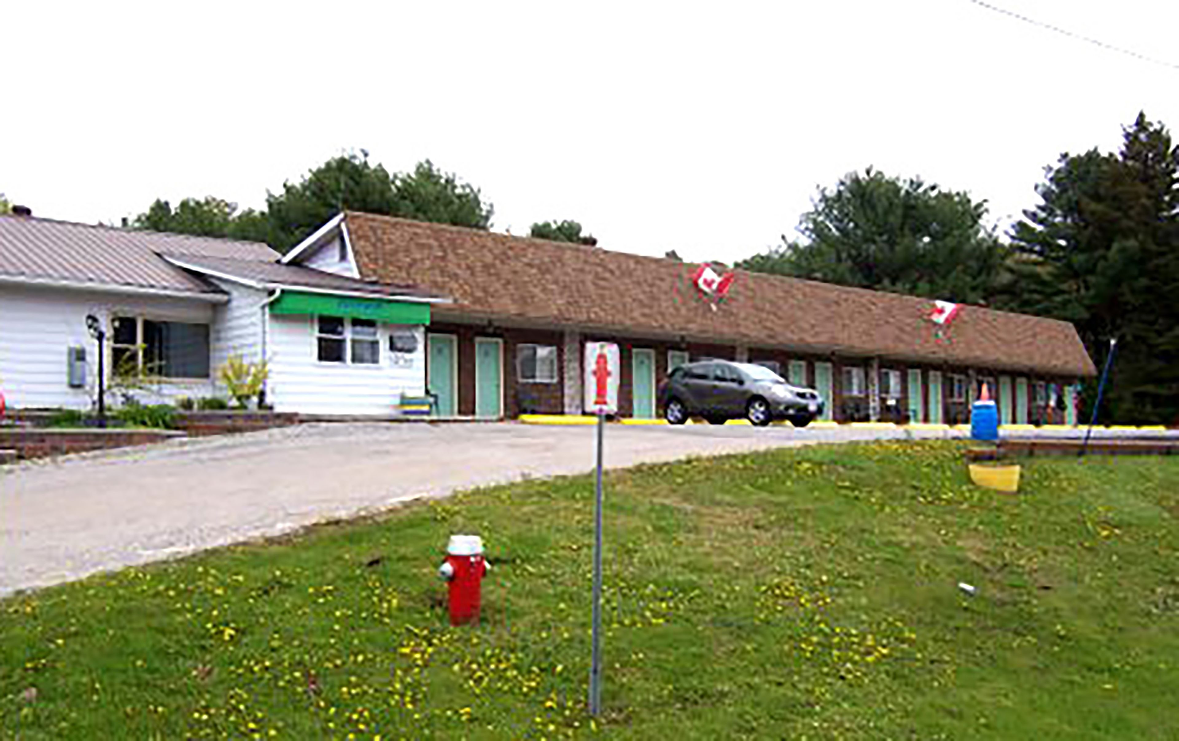 A motel with a single-story structure, a green awning, and a red fire hydrant in the foreground.