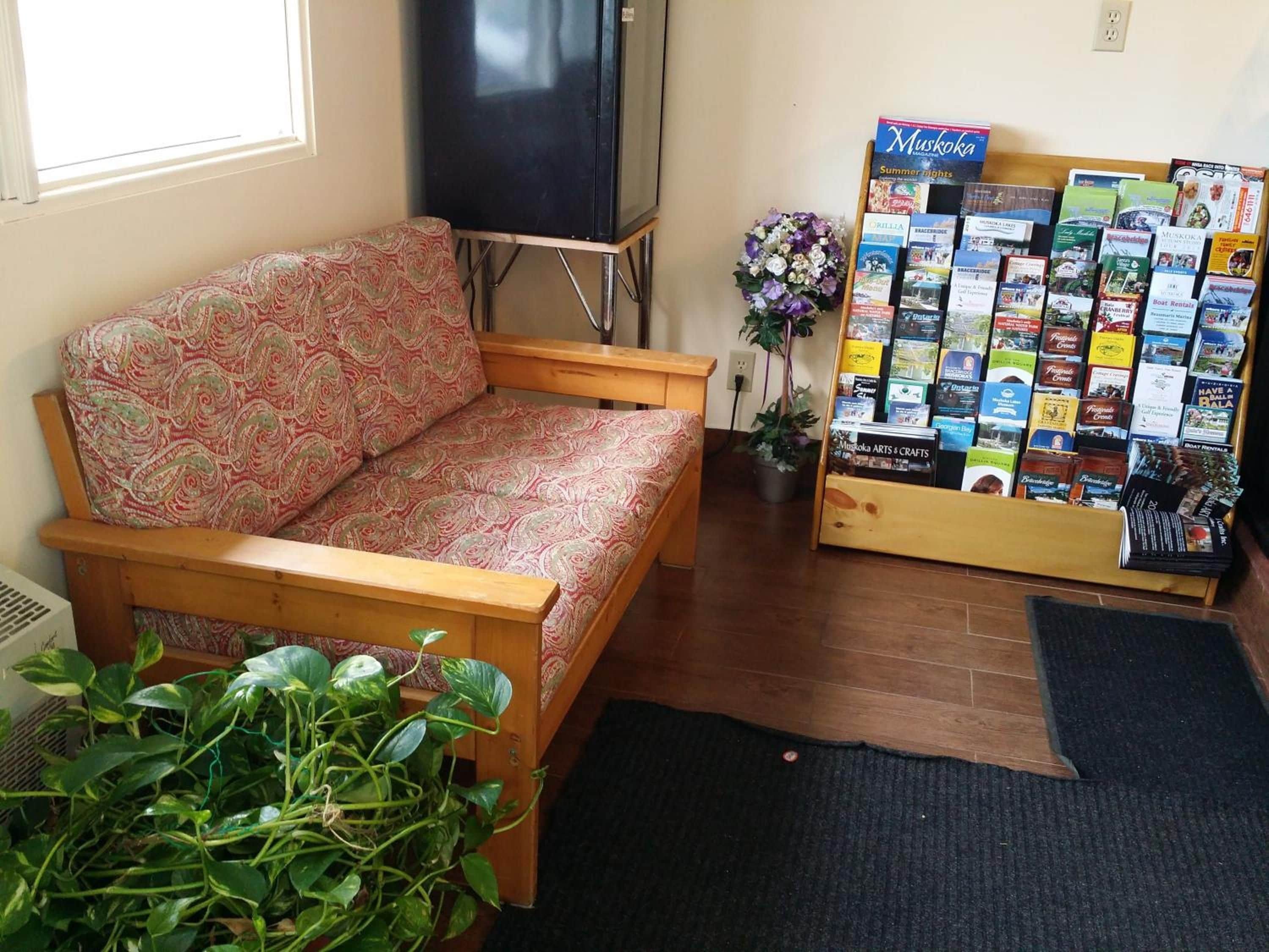 Un salon comprenant un canapé, un téléviseur, une plante et une collection de brochures de voyage.