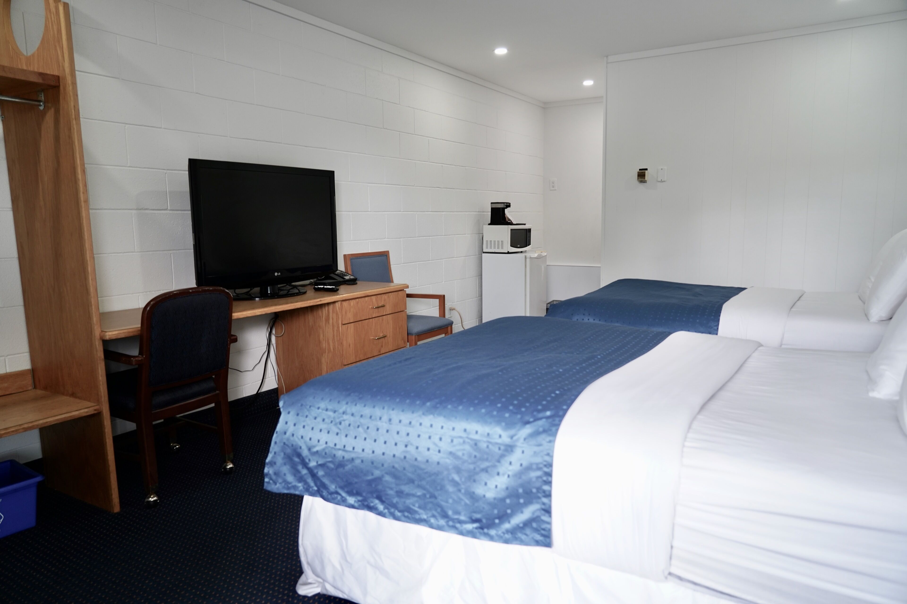 A hotel room with two beds, a desk with a computer, a television, and a microwave.