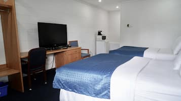A hotel room with two beds, a desk with a computer, a television, and a microwave.