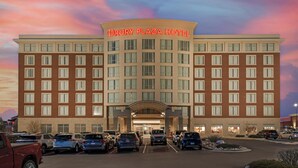 A hotel with a prominent sign, multiple floors, and a parking lot.