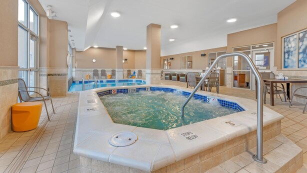A hotel lobby with a large indoor pool, seating areas, and a reception desk.