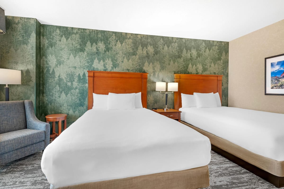 Une chambre d’hôtel avec deux lits, un canapé, une lampe et une petite table.