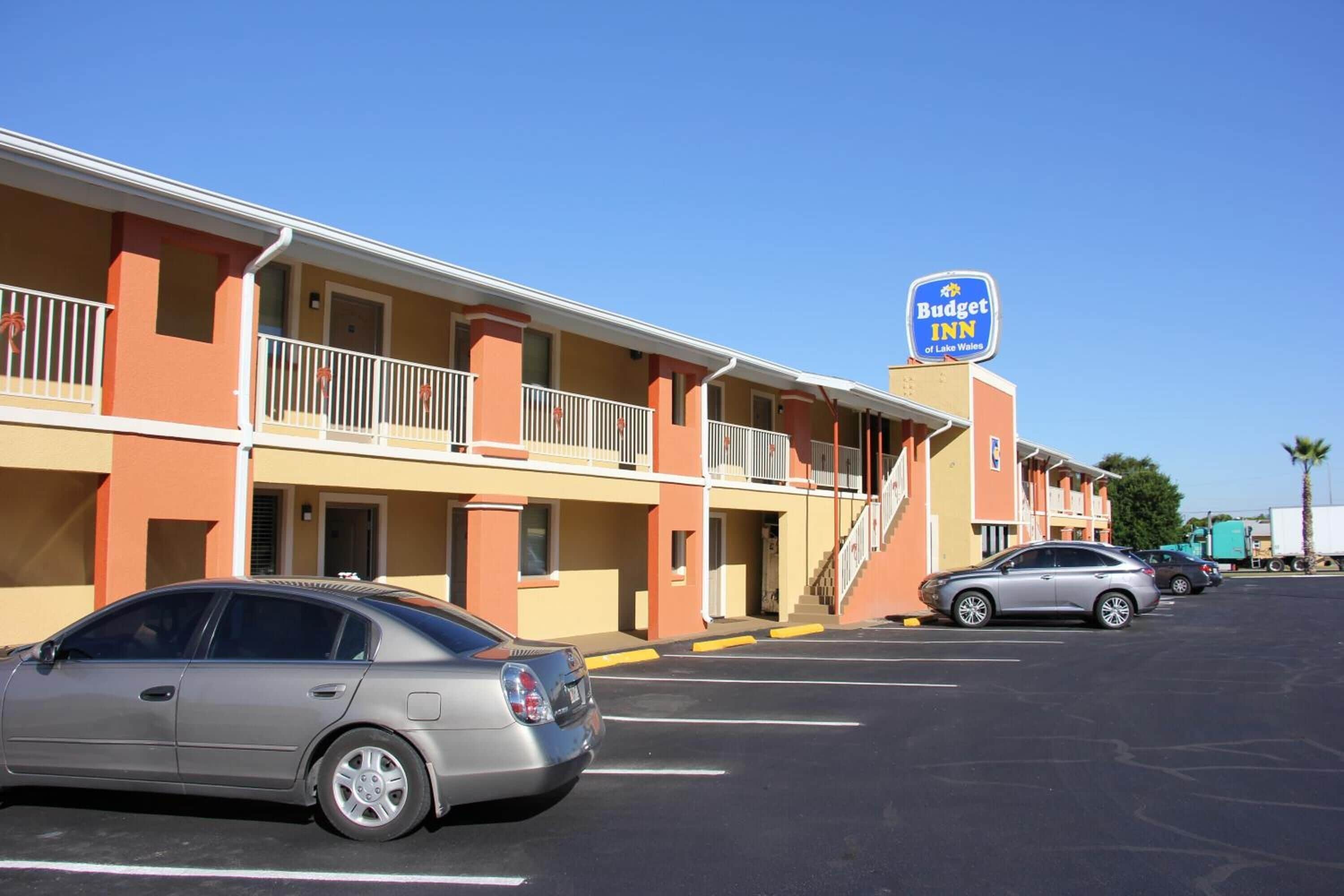 A Budget Inn hotel with a two-story structure, a parking lot, and a clear blue sky.