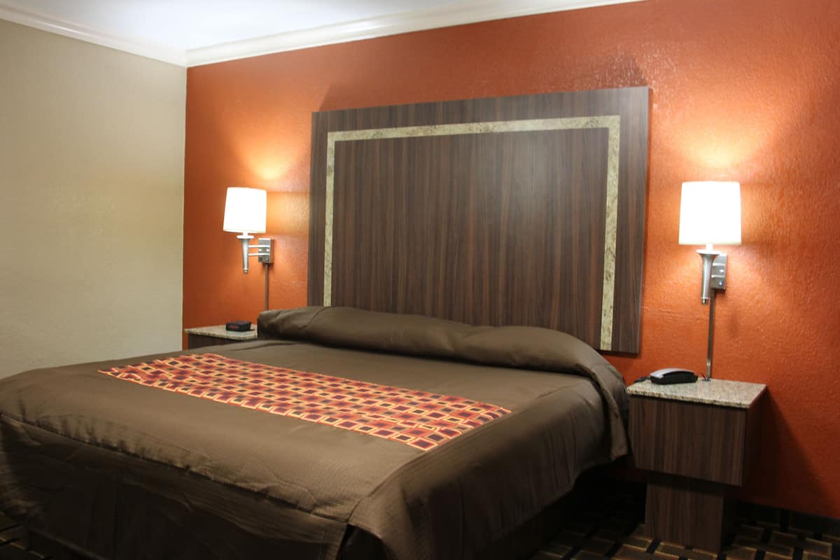A hotel room with a large bed, two bedside tables with lamps, and a wooden headboard.