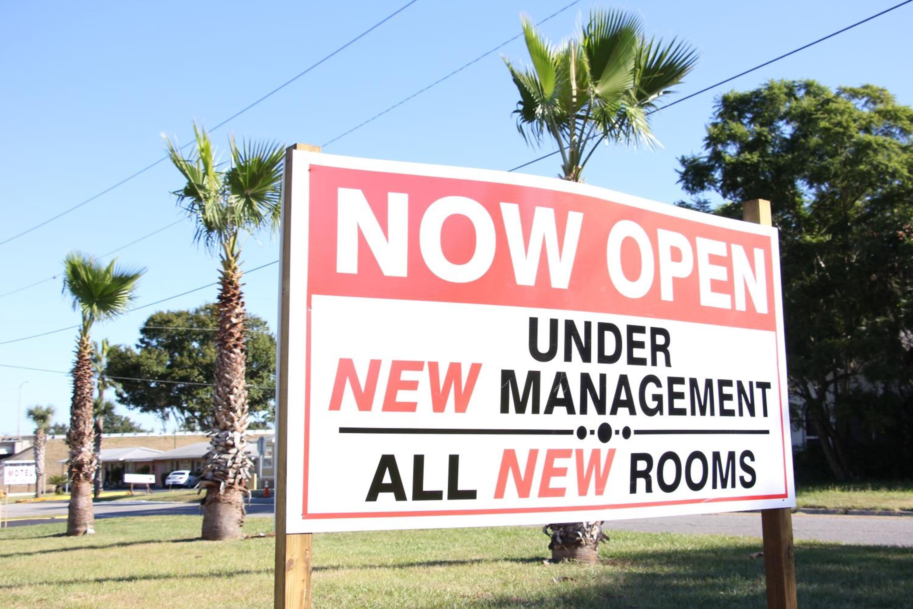 A sign advertising "NOW OPEN UNDER NEW MANAGEMENT ALL NEW ROOMS".