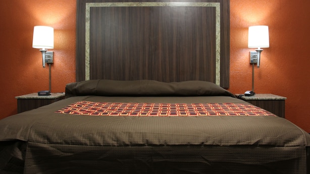 A hotel room with a large bed, two bedside tables with lamps, and a wooden headboard.