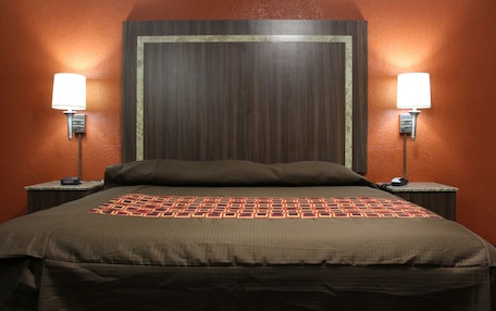 A hotel room with a large bed, two bedside tables with lamps, and a wooden headboard.