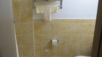 A bathroom with beige tiles, a toilet, a bidet, and a towel rack with two towels.