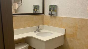 A bathroom with a toilet, sink, and mirror.