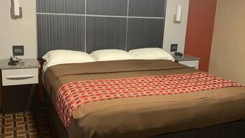 Una habitación de hotel con una cama, una mesita de noche y un teléfono instalado en la pared.