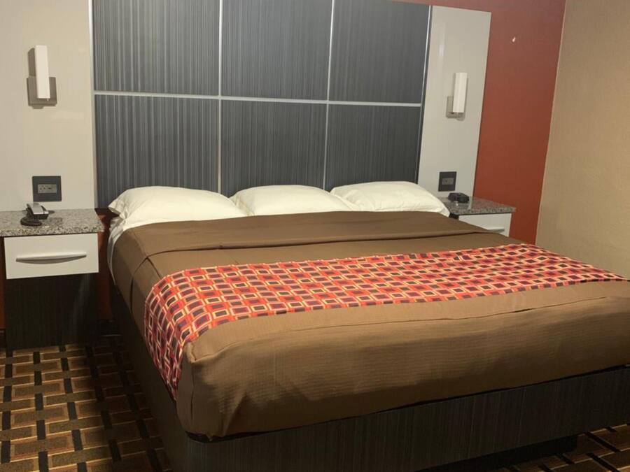 Una habitación de hotel con una cama, una mesita de noche y un teléfono instalado en la pared.