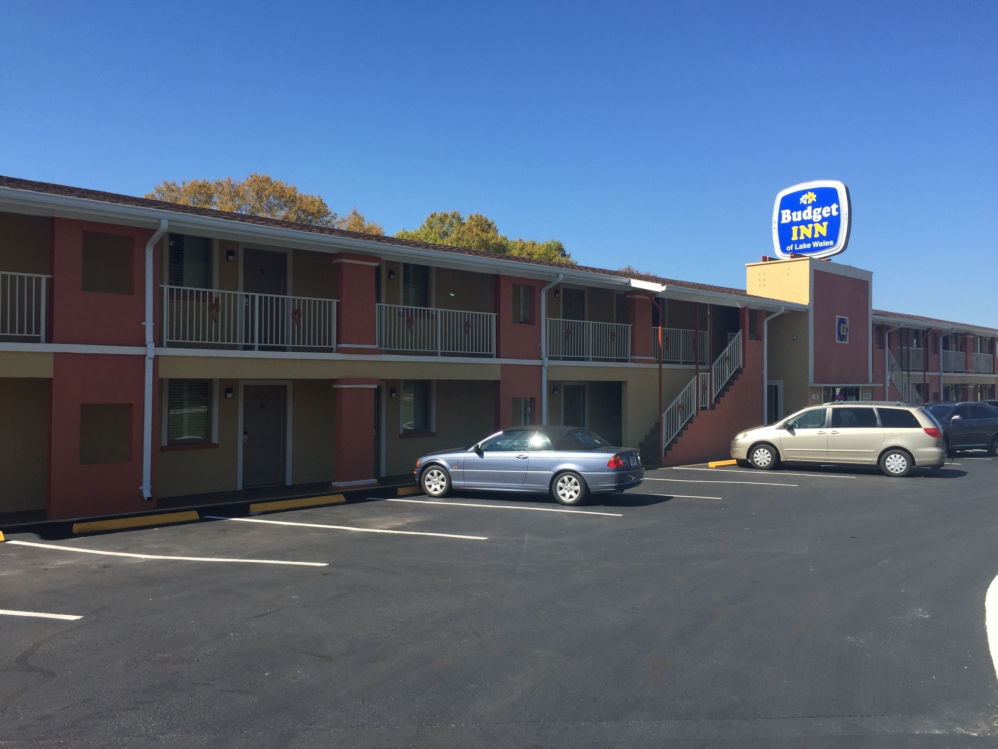 A motel with a two-story building, a parking lot, and a sign for Budget Inn of Lake Wales.