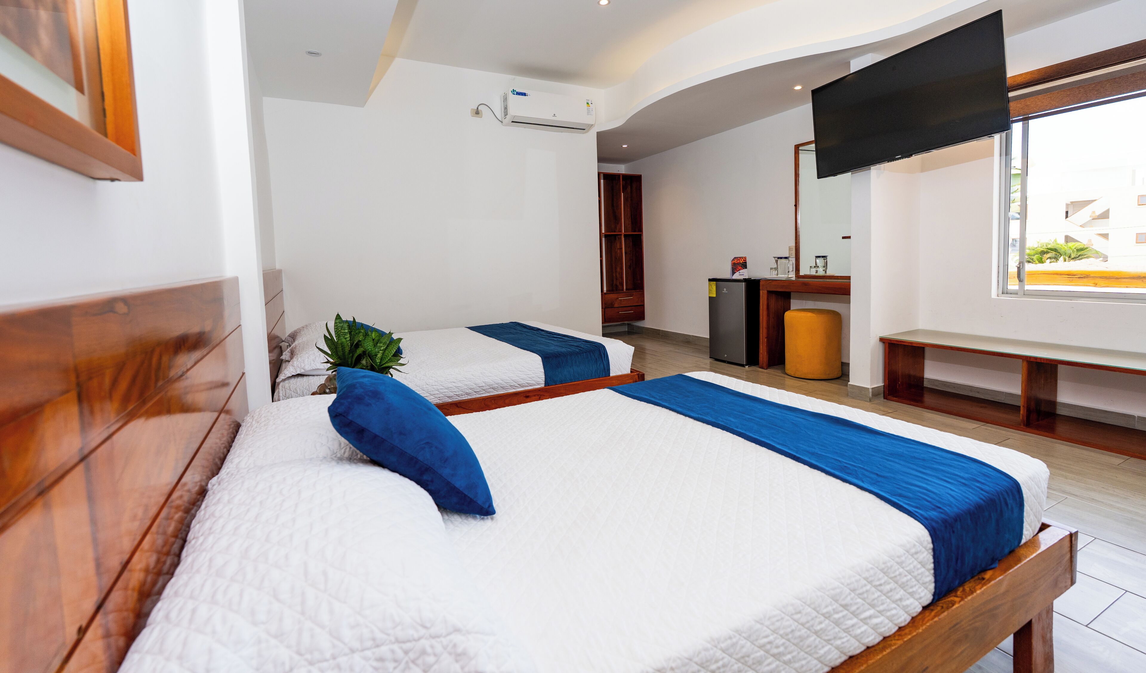 Una habitación de hotel con dos camas, un pequeño rincón de cocina, un espejo y una ventana con vistas.