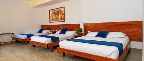 Una habitación de hotel con tres camas de madera, cada una con ropa de cama blanca y azul.