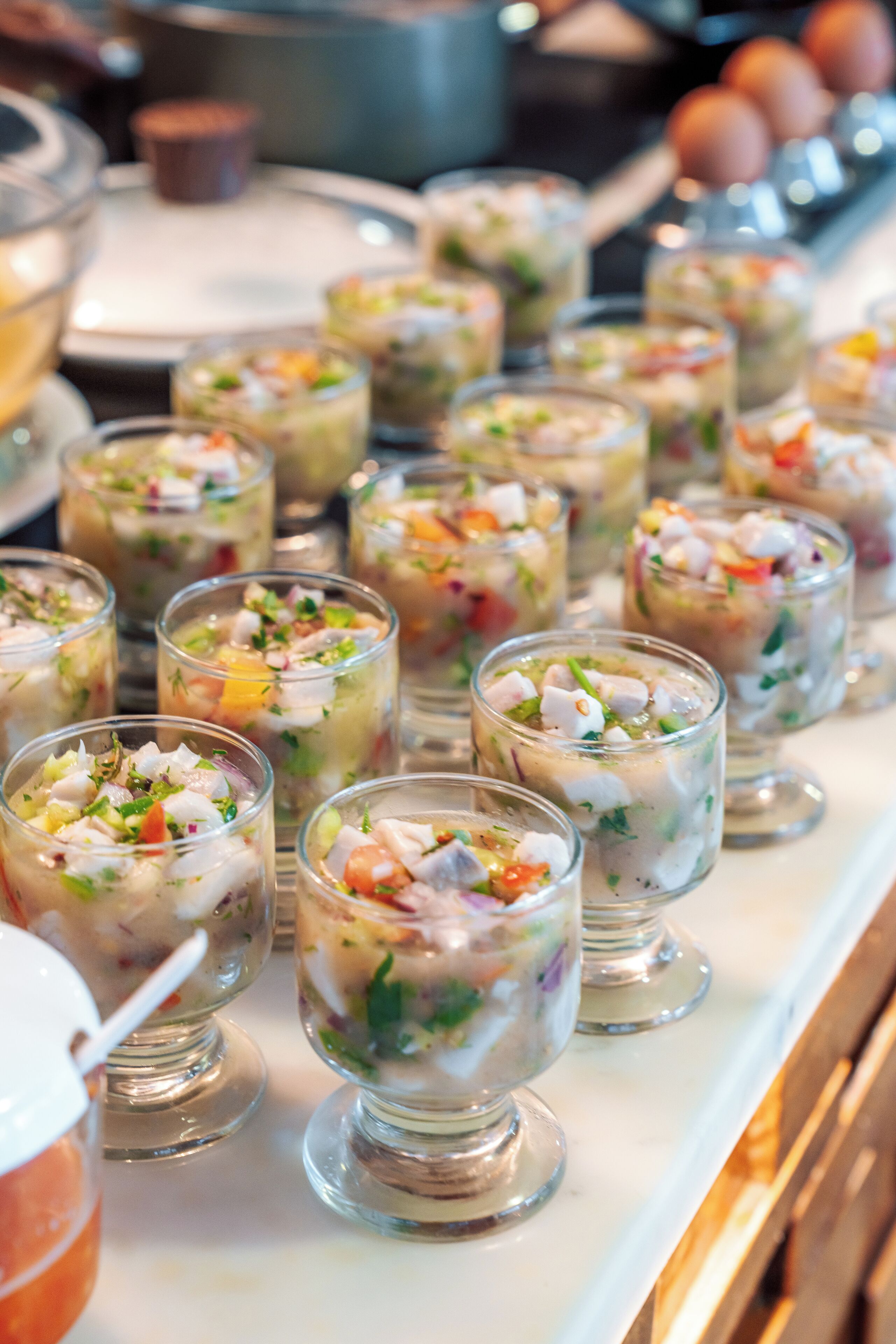 Una mesa de buffet con diversos platos, incluyendo una ensalada de mariscos y una de frutas.