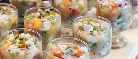 Una mesa de buffet con diversos platos, incluyendo una ensalada de mariscos y una de frutas.