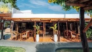 Een restaurant met terras, een houten pergola en potplanten.
