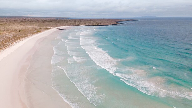 Een strand met helder turquoise water en een zandstrand.