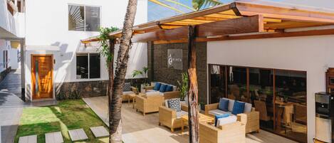 Un espacio moderno al aire libre con patio, asientos y una palmera.
