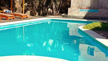 Una piscina con lettini e palme.
