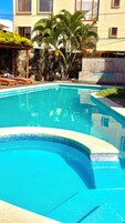 Une piscine avec des chaises longues et des palmiers.
