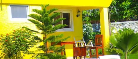 Un edificio amarillo con un porche pequeño, una ventana y una puerta.
