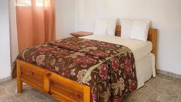 A bedroom with a wooden bed frame, a floral bedspread, and a nightstand.