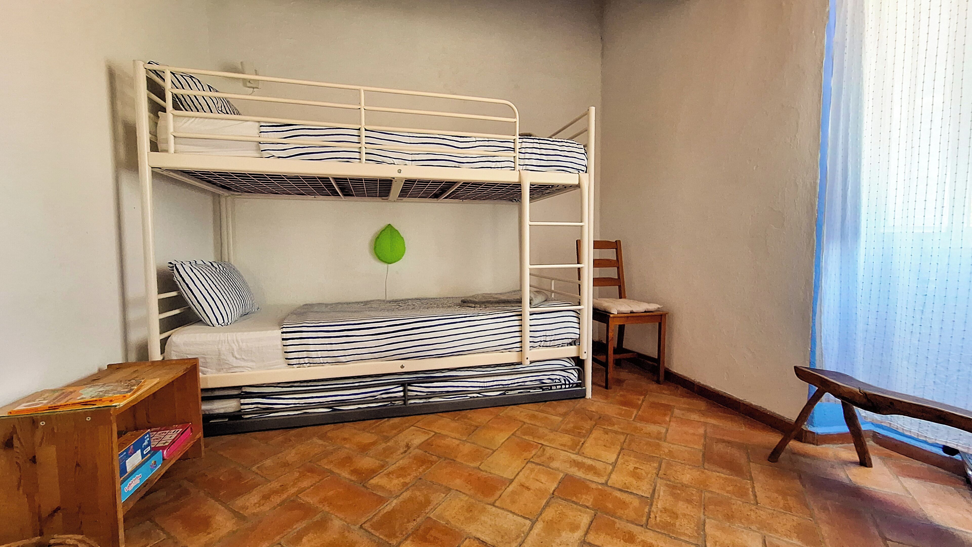Une chambre avec un lit superposé, une chaise en bois et une petite table.