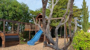 A playground with a wooden slide and a swing set. - Quinta da Fornalha (Castro Marim)