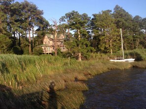 Una casa junto a un río con una barca amarrada cerca.