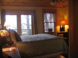 Una habitación acogedora con una cama, un escritorio con lámpara, una ventana con persianas y vistas al exterior.