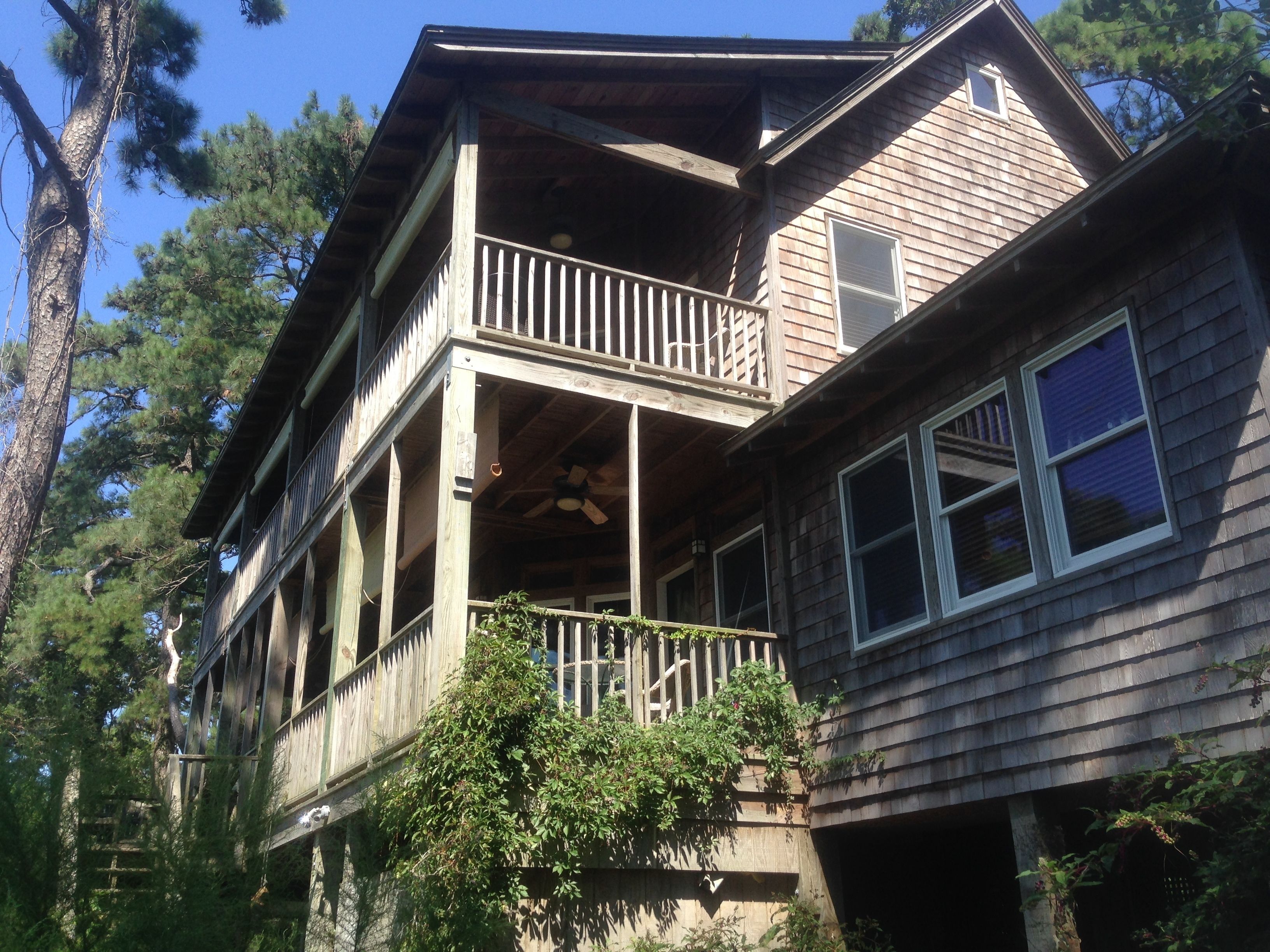 A two-story wooden house with a balcony, a front porch, and a garage.