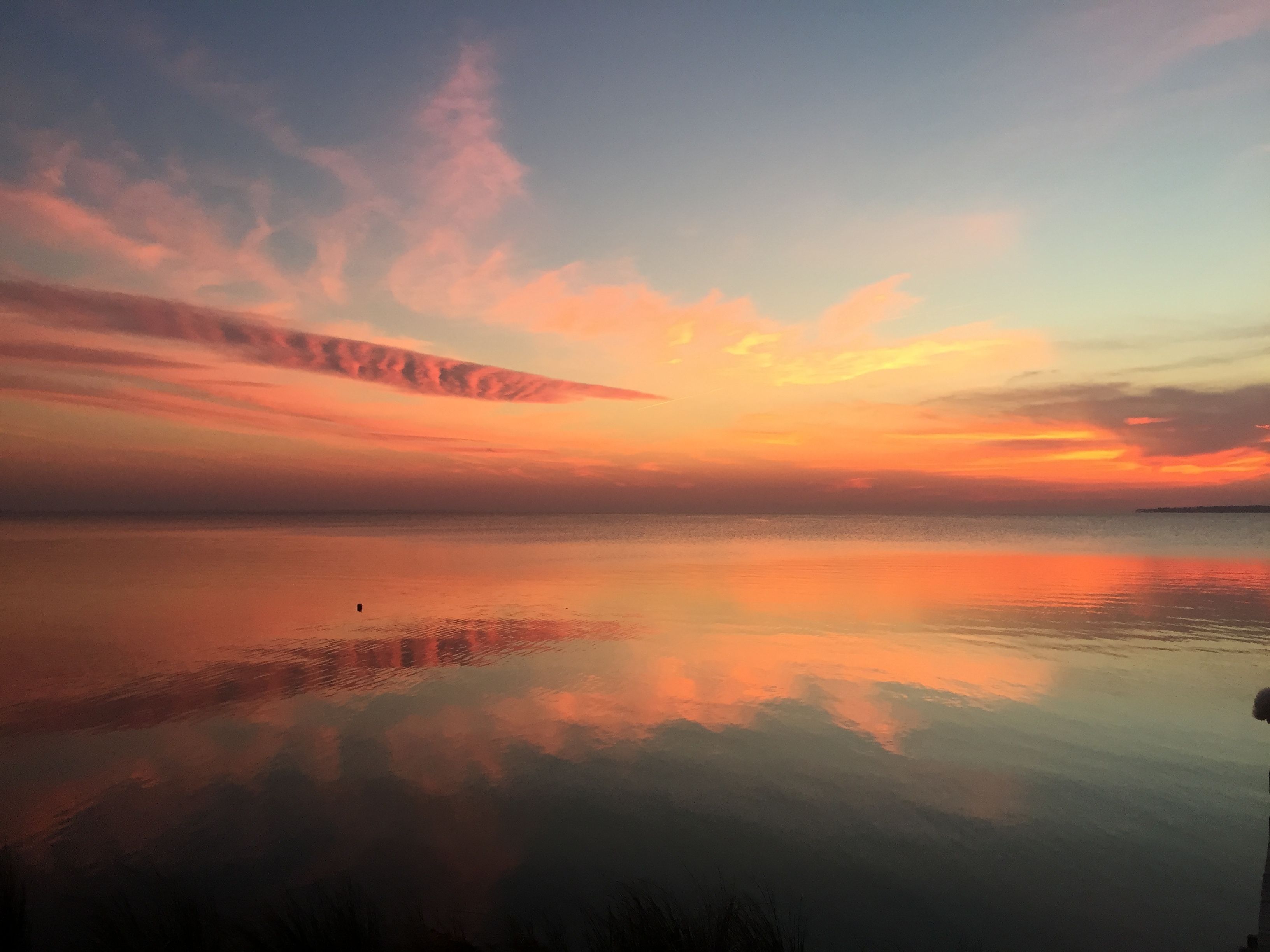 Un'acqua calma che riflette un cielo al tramonto con nuvole.