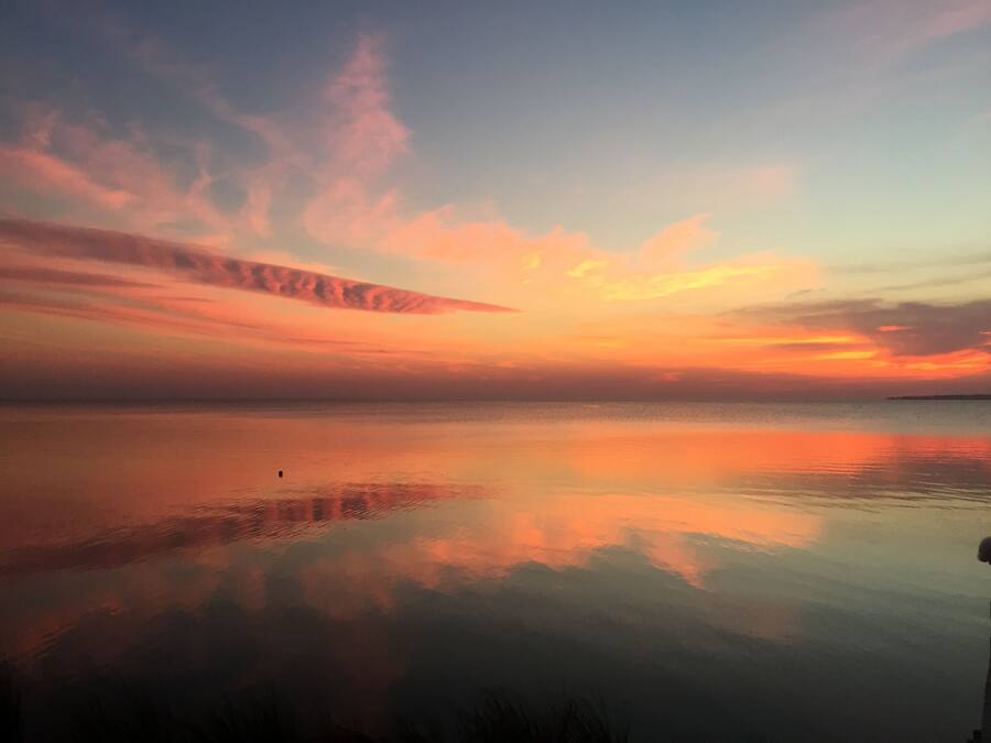 Un'acqua calma che riflette un cielo al tramonto con nuvole.