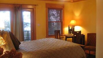 A bedroom with a bed, a desk, a chair, a lamp, and a window with blinds.