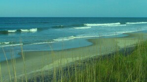 A beach with waves, sand, and grass. - Cypress Moon Inn (Kitty Hawk)