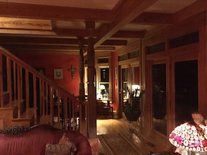 A staircase leading to a second floor with wooden railings and a red wall with a cross.