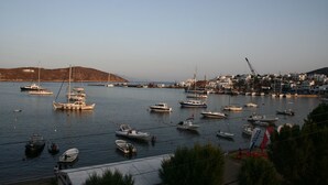A harbor with various boats and yachts docked, a small island in the background, and a town with buildings along the waterfront. - Cyclades Hotel Serifos (Serifos)
