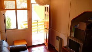 Une pièce comprenant un canapé, un téléviseur, un radiateur et une porte donnant sur l’extérieur.