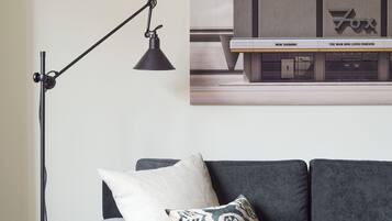 Una sala de estar moderna con un sofá gris, una lámpara de pie y un cartel de cine.