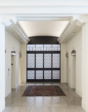 A spacious hallway with a patterned black and white partition, light-colored walls, and a patterned rug on the floor. - ROOST Midtown (Philadelphia)