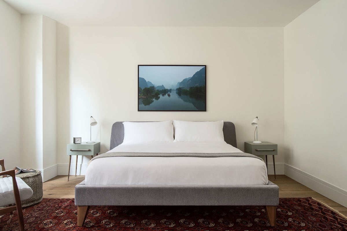 A neatly arranged bedroom with a large bed, two bedside tables, and a framed picture on the wall.