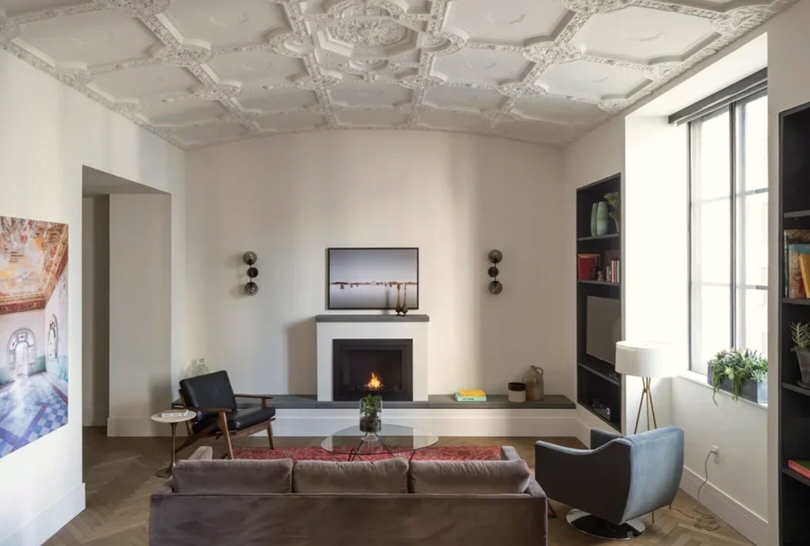 A living room with a fireplace, a sofa, a chair, and a bookshelf.