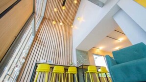 Een modern interieur met een schuin dak, houten lambrisering en gele stoelen.