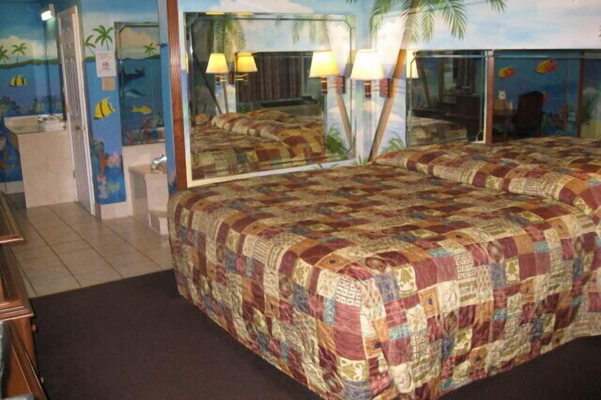 Un dormitorio con una cama grande, un espejo y vistas al baño.