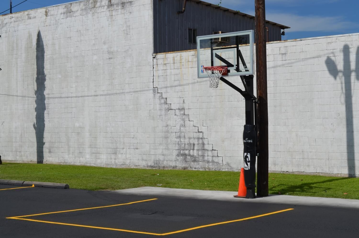 Ein Basketballkorb ist an einer Betonwand angebracht, und eine Treppe führt zu einer Tür.