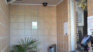 A bathroom with a potted plant, a standing heater, a security camera, and a payment terminal. - Economy Inn (New Orleans)