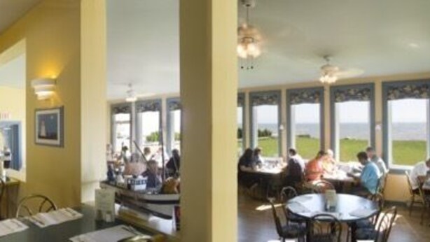 Un restaurante con varias salas de comedor, ventiladores de techo y ventanas amplias que ofrecen vistas al exterior.